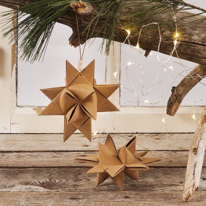 Una stella di Natale intrecciata con strisce di carta in finta pelle e cordino in cuoio con perle in legno per appenderla