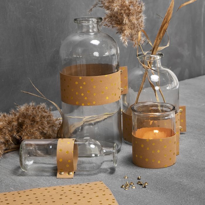 Bottiglie in vetro e portacandele decorati con carta in finta pelle