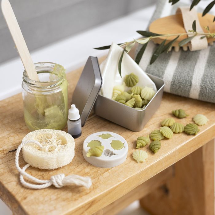 Contenitore da viaggio con piccoli saponi all'olio d'oliva e spugna di loofah