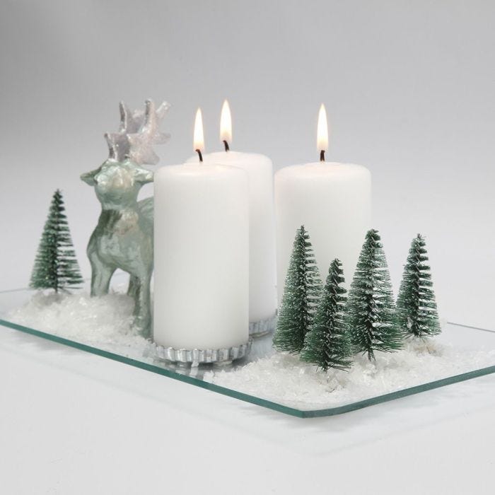 Decoro natalizio con candele, renna, alberi e neve su piatto in vetro