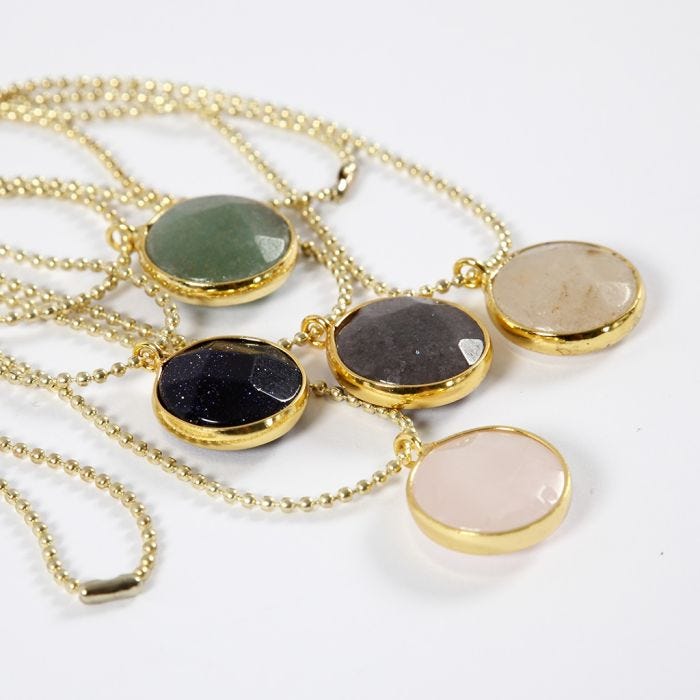 Una collana con catenella a perline e pendente gioiello con pietra