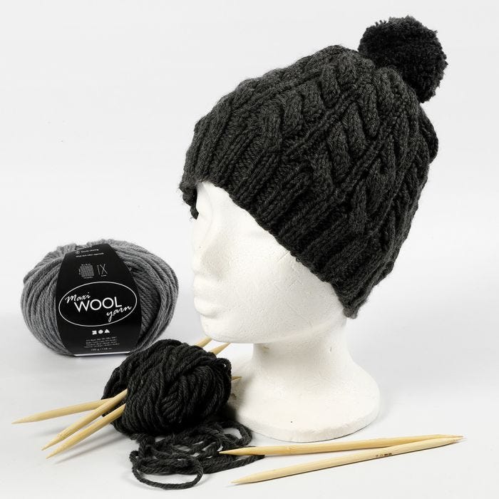 Un cappello lavorato a maglia con un motivo a trecce e un pom-pom