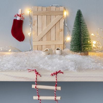La porta di un elfo di bastoncini del ghiacciolo con una scala di corda e una cassetta delle lettere a calza di Natale