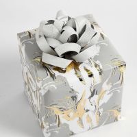 Confezione regalo decorata con una coccarda realizzata con strisce di carta per stelle