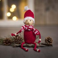 Un elfo a maglia in filato acrilico con perline di legno per mani e piedi 