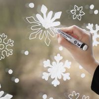 Decorazione della finestra con fiocchi di neve con pennarelli a gesso 